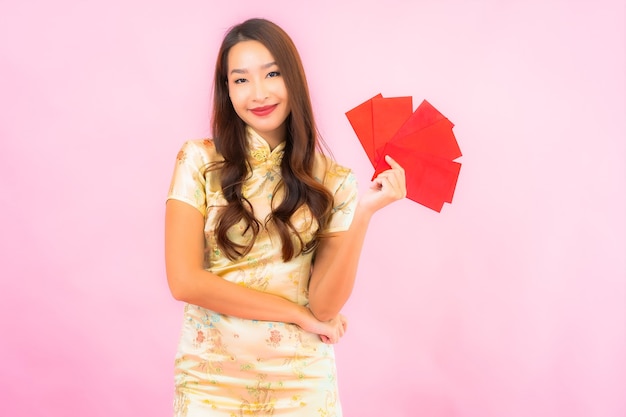 Retrato hermosa joven asiática con sobres rojos en la pared rosa