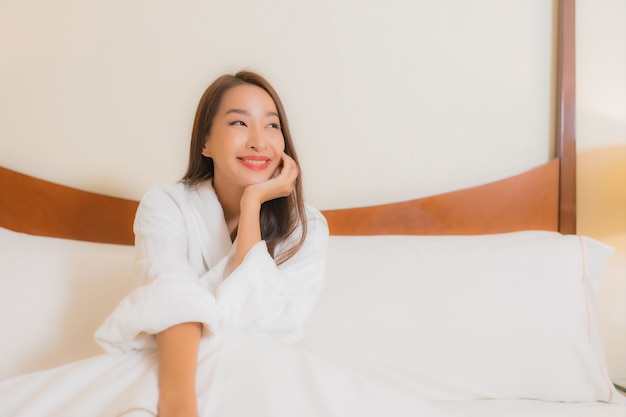 Retrato hermosa joven asiática sonríe relajante en la cama en el interior del dormitorio