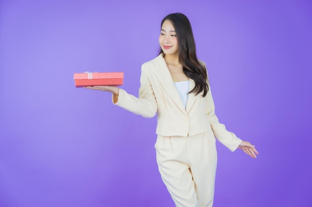 Retrato hermosa joven asiática sonrisa con caja de regalo roja sobre fondo de color