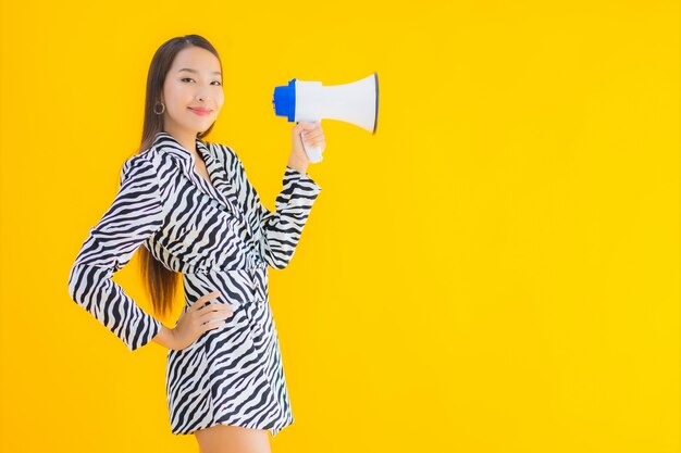 Retrato hermosa joven asiática sonrisa feliz con megáfono en amarillo