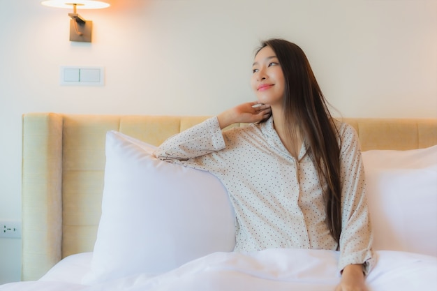 Retrato hermosa joven asiática sonrisa feliz relajarse en la cama