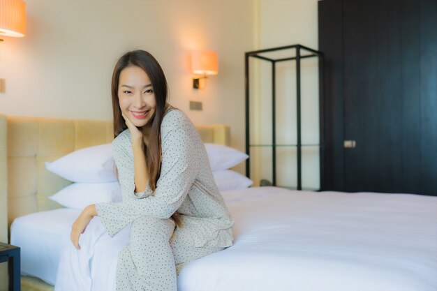 Retrato hermosa joven asiática sonrisa feliz relajarse en la cama