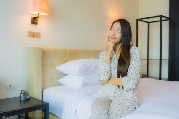 Retrato hermosa joven asiática sonrisa feliz relajarse en la cama