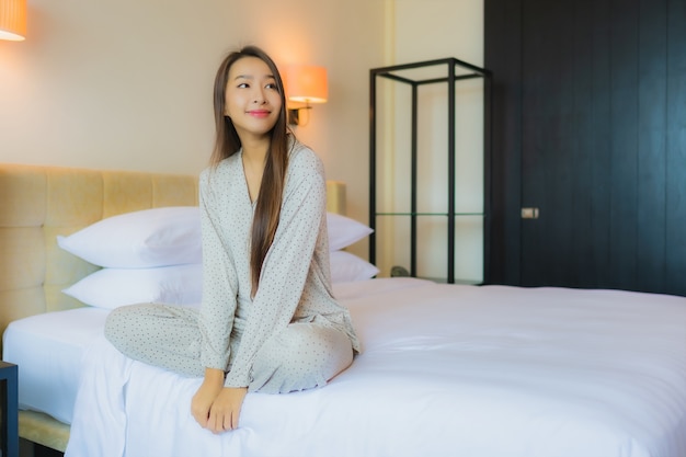 Retrato hermosa joven asiática sonrisa feliz relajarse en la cama