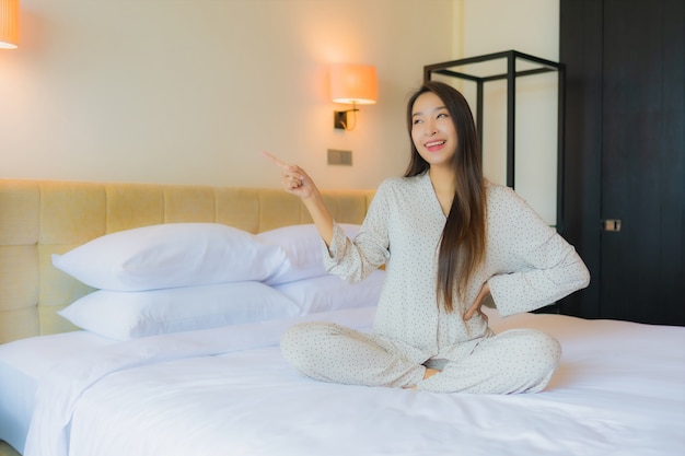 Retrato hermosa joven asiática sonrisa feliz relajarse en la cama