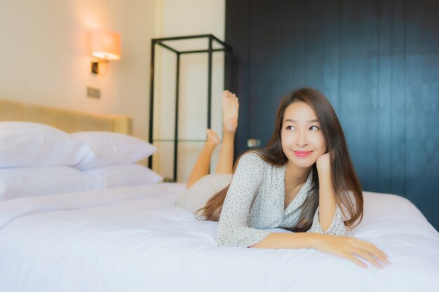 Retrato hermosa joven asiática sonrisa feliz relajarse en la cama