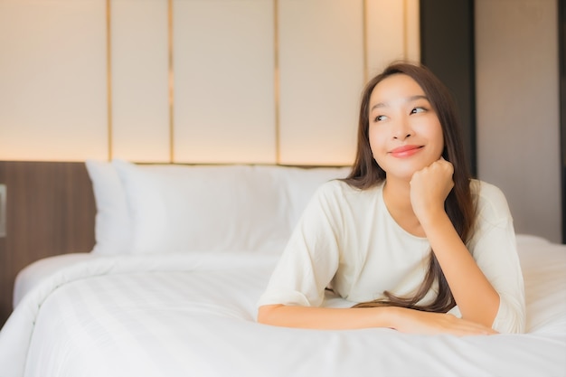 Retrato hermosa joven asiática sonrisa relajarse ocio en la cama en el interior del dormitorio