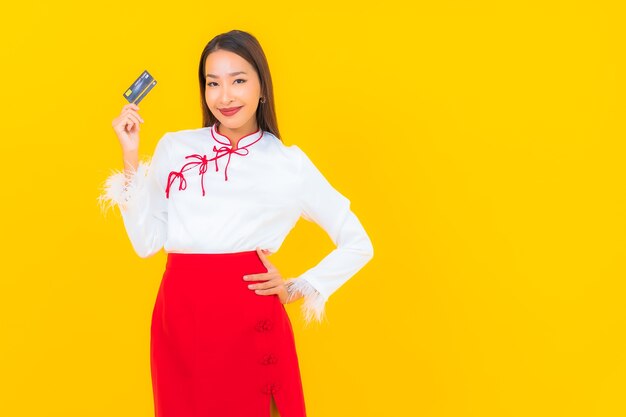 Retrato hermosa joven asiática con tarjeta de crédito para compras en línea en amarillo