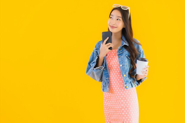 Retrato hermosa joven asiática con taza de café y teléfono inteligente