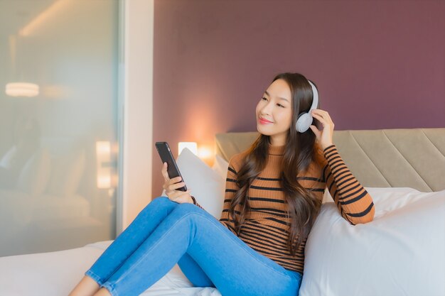 Retrato hermosa joven asiática usa auriculares para escuchar música en la cama