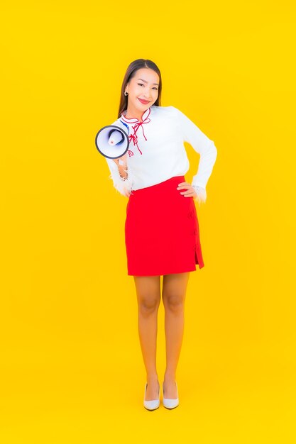 Retrato hermosa joven asiática usa megáfono en amarillo