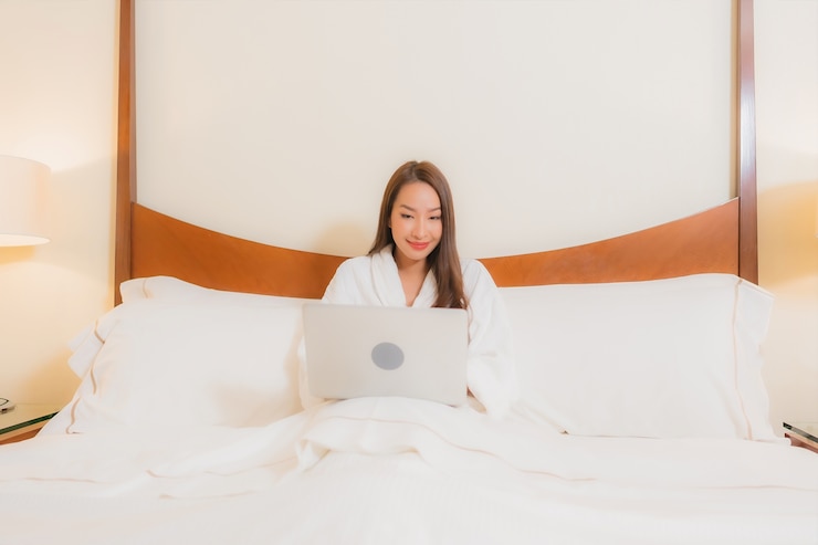 Foto gratuito retrato hermosa joven asiática usando laptop en la cama en el interior del dormitorio