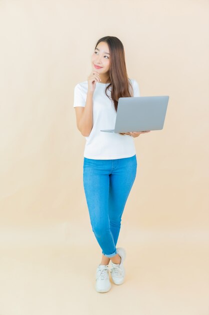 Retrato hermosa joven asiática usar computadora portátil en beige