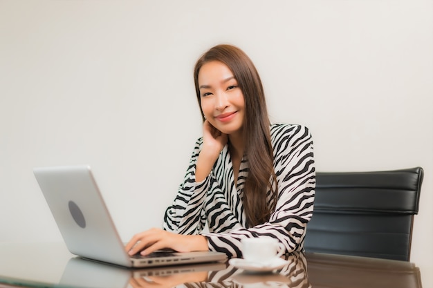 Retrato hermosa joven asiática usar computadora portátil en la mesa de trabajo en la habitación