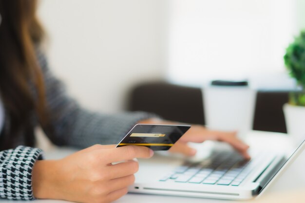 Retrato hermosa joven asiática usar tarjeta de crédito con laptop para compras en línea