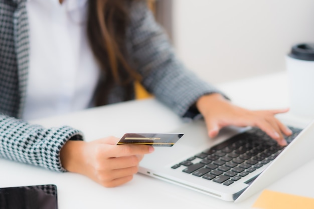 Retrato hermosa joven asiática usar tarjeta de crédito con laptop para compras en línea