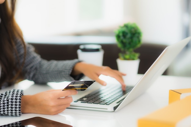 Retrato hermosa joven asiática usar tarjeta de crédito con laptop para compras en línea