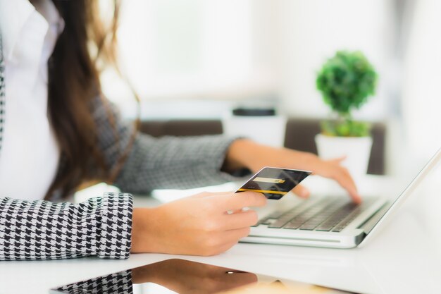 Retrato hermosa joven asiática usar tarjeta de crédito con laptop para compras en línea