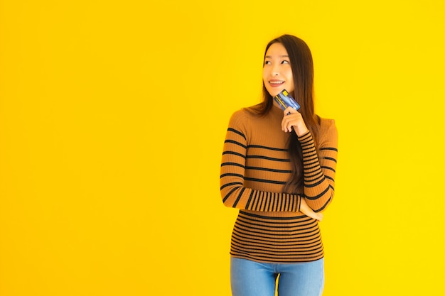 Retrato hermosa joven asiática usar teléfono móvil inteligente o teléfono celular con tarjeta de crédito para compras en línea