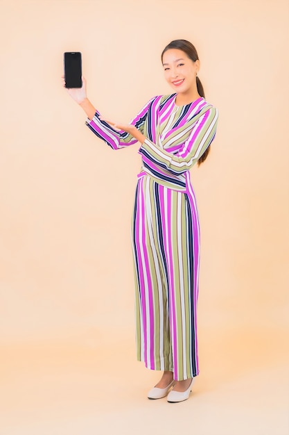 Retrato hermosa joven asiática utiliza teléfono móvil inteligente en color