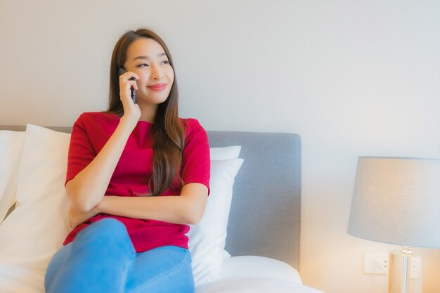 Retrato hermosa joven asiática utilizar teléfono móvil inteligente en la cama