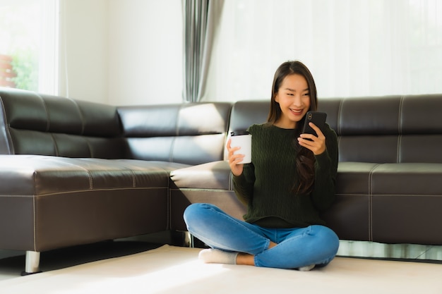 Retrato hermosa joven asiática utilizar teléfono móvil inteligente con taza de café