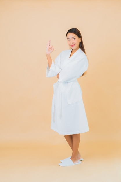 Retrato hermosa joven asiática vistiendo bata de baño con sonrisa en beige