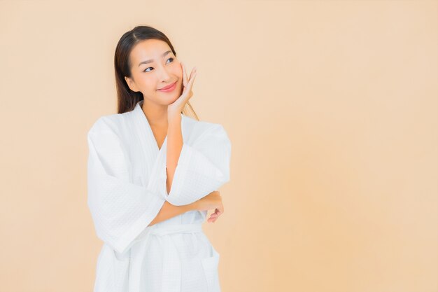 Retrato hermosa joven asiática vistiendo bata de baño con sonrisa en beige