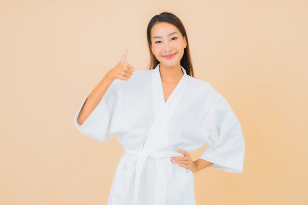 Retrato hermosa joven asiática vistiendo bata de baño con sonrisa en beige