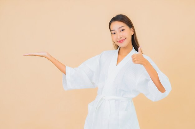 Retrato hermosa joven asiática vistiendo bata de baño con sonrisa en beige