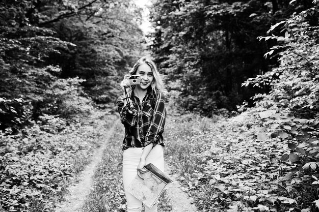 Retrato de una hermosa joven con camisa de tartán tomando fotos con cámara en el bosque