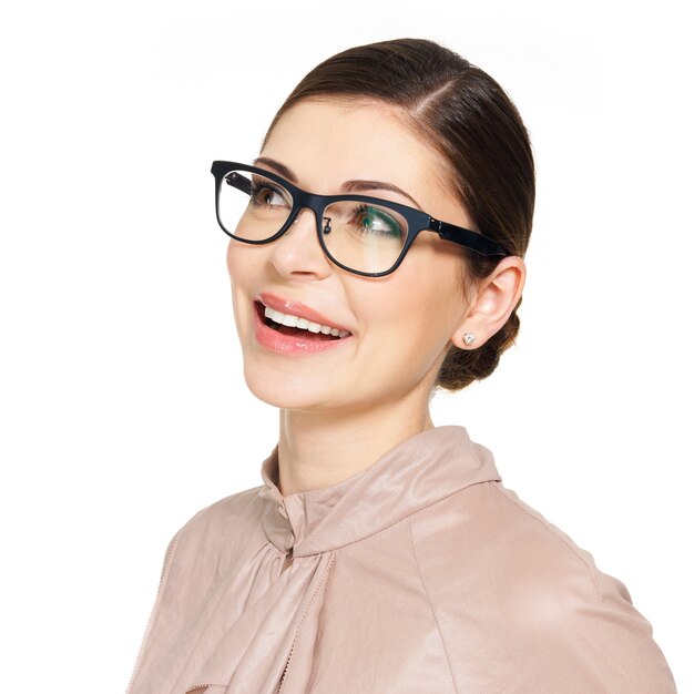 Retrato de la hermosa joven feliz con gafas y camisa beige mirando hacia arriba, aislado sobre fondo blanco.