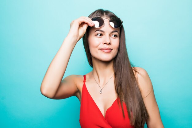 Retrato de una hermosa joven con gafas de sol en una pared azul