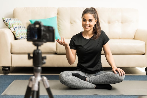 Retrato de una hermosa joven instructora de yoga grabando un video para su blog en casa