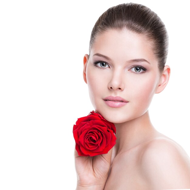 Retrato de una hermosa joven morena con rosa roja cerca de la cara - aislado en blanco.