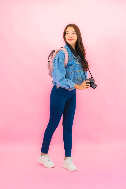 Retrato hermosa joven mujer asiática mochila o equipaje con cámara lista para viajar en vacaciones en pared rosa