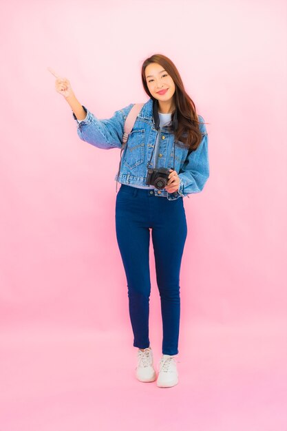 Retrato hermosa joven mujer asiática mochila o equipaje con cámara lista para viajar en vacaciones en pared rosa