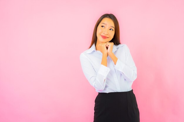Retrato hermosa joven mujer asiática de negocios con acción rosa pared aislada