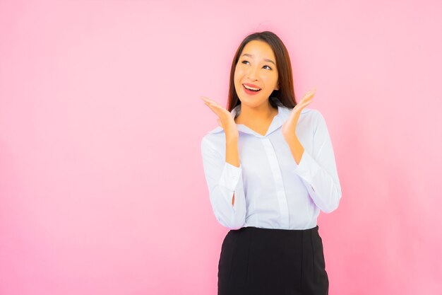 Retrato hermosa joven mujer asiática de negocios con acción rosa pared aislada