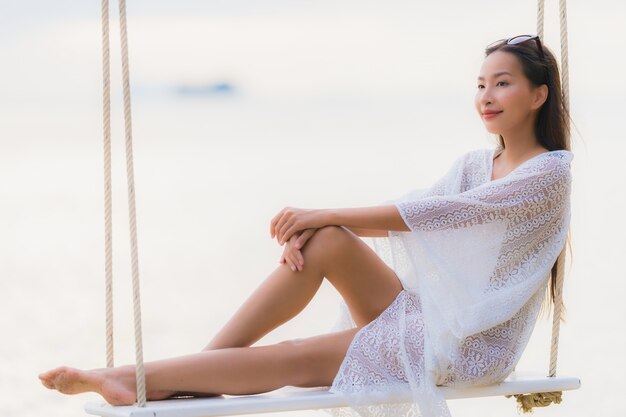 Retrato hermosa joven mujer asiática sentada en el columpio alrededor de la playa del mar océano para relajarse