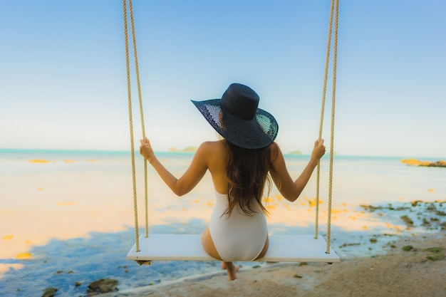 Retrato hermosa joven mujer asiática sentada en el columpio alrededor de la playa del mar océano para relajarse