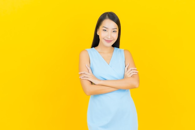 Retrato hermosa joven mujer asiática sonríe con acción en la pared de color amarillo