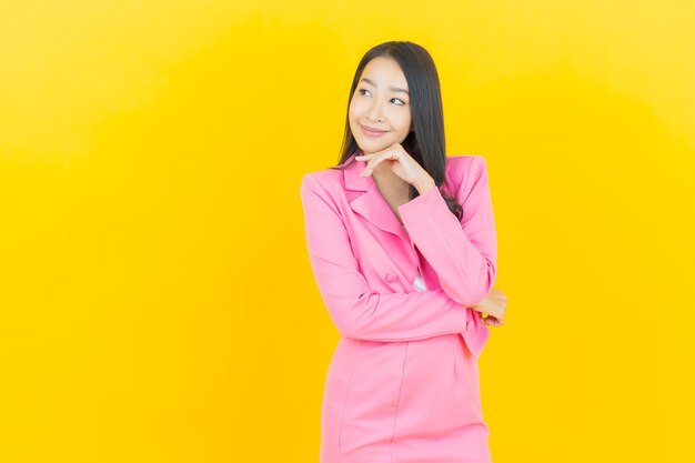 Retrato hermosa joven mujer asiática sonríe con acción en la pared de color amarillo