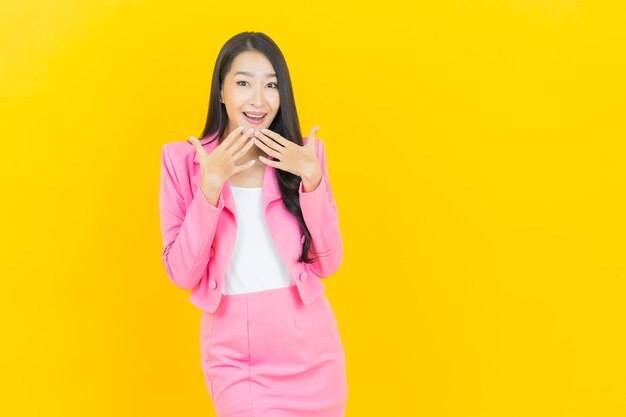 Retrato hermosa joven mujer asiática sonríe con acción en la pared de color amarillo