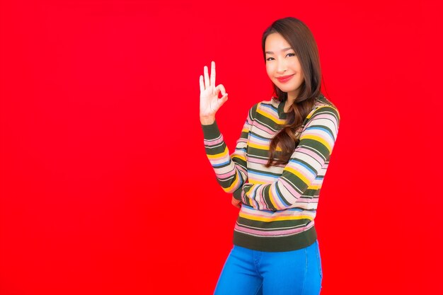 Retrato hermosa joven mujer asiática sonríe con acción en la pared roja aislada