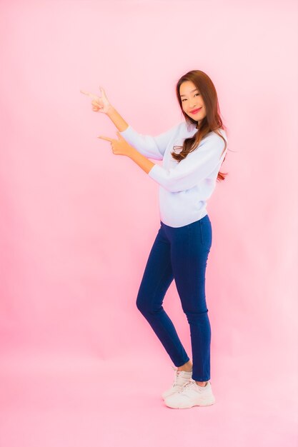 Retrato hermosa joven mujer asiática sonríe con acción en rosa pared aislada