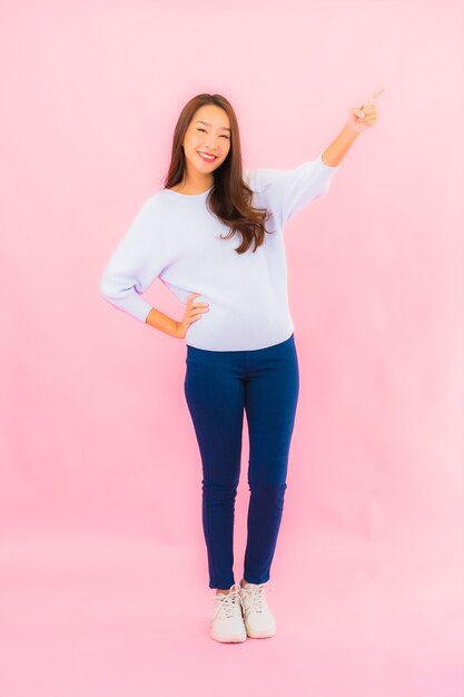 Retrato hermosa joven mujer asiática sonríe con acción en rosa pared aislada