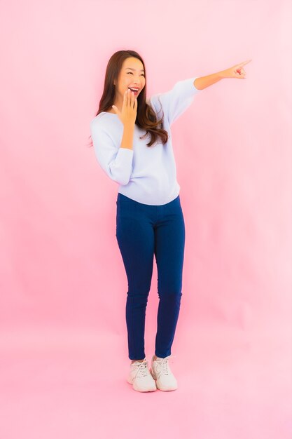 Retrato hermosa joven mujer asiática sonríe con acción en rosa pared aislada