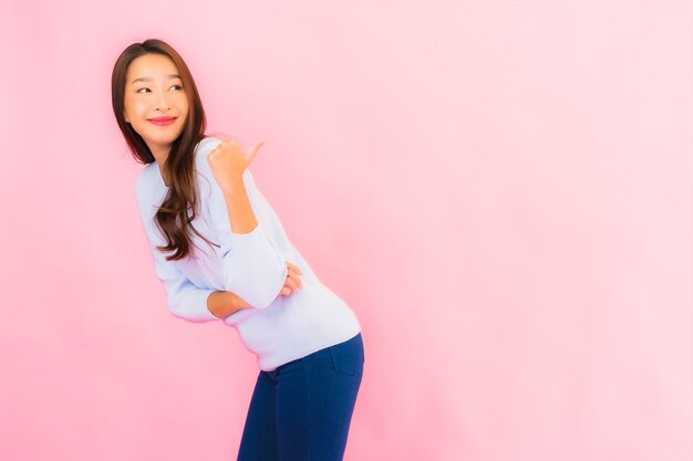 Retrato hermosa joven mujer asiática sonríe con acción en rosa pared aislada