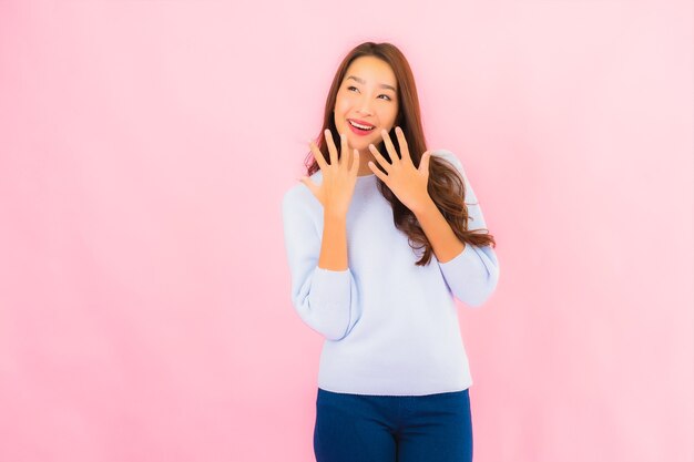 Retrato hermosa joven mujer asiática sonríe con acción en rosa pared aislada